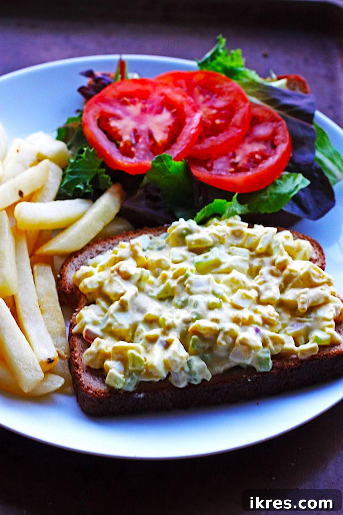 Quick Creamy Egg Salad 5 Easy Egg Salad on a piece of toast with lettuce, tomato, and a side of fries.