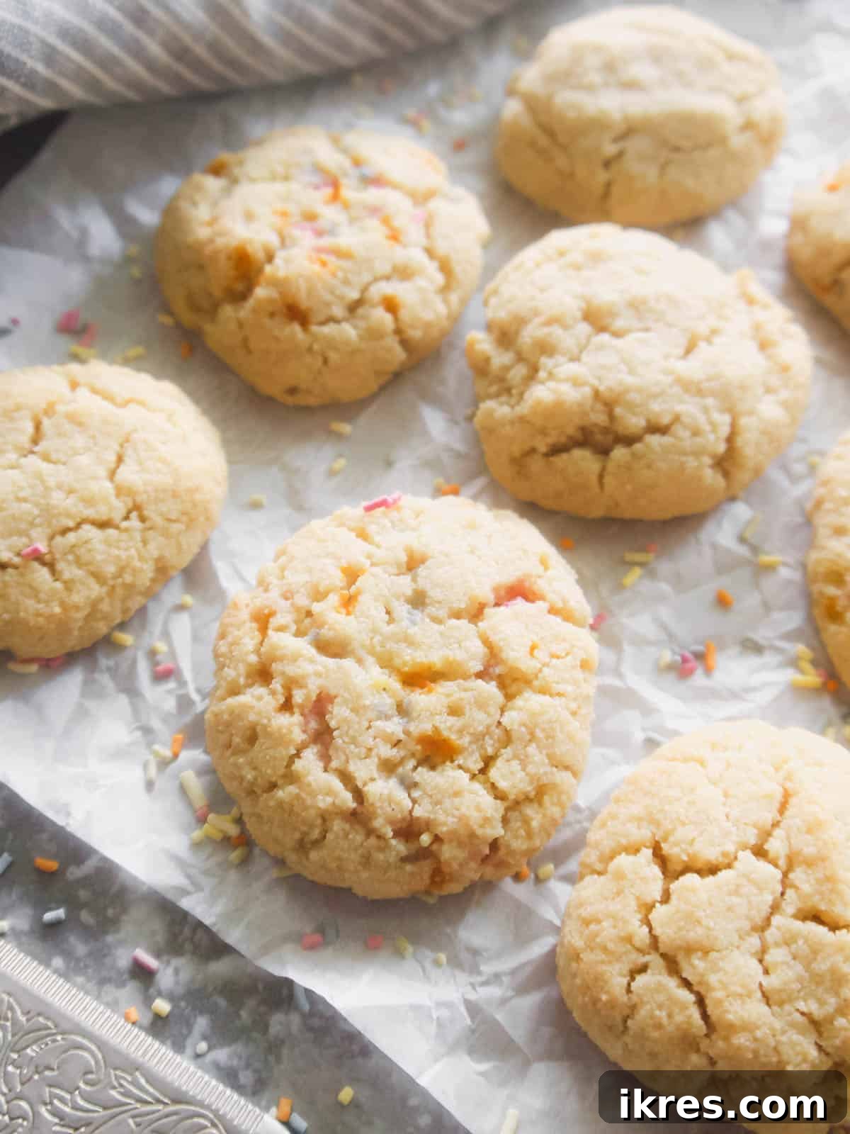 Delicious Paleo and Gluten Free Sugar Cookies 2 Paleo sugar cookies on parchment paper with colorful sprinkles, suggesting a festive and healthy treat.