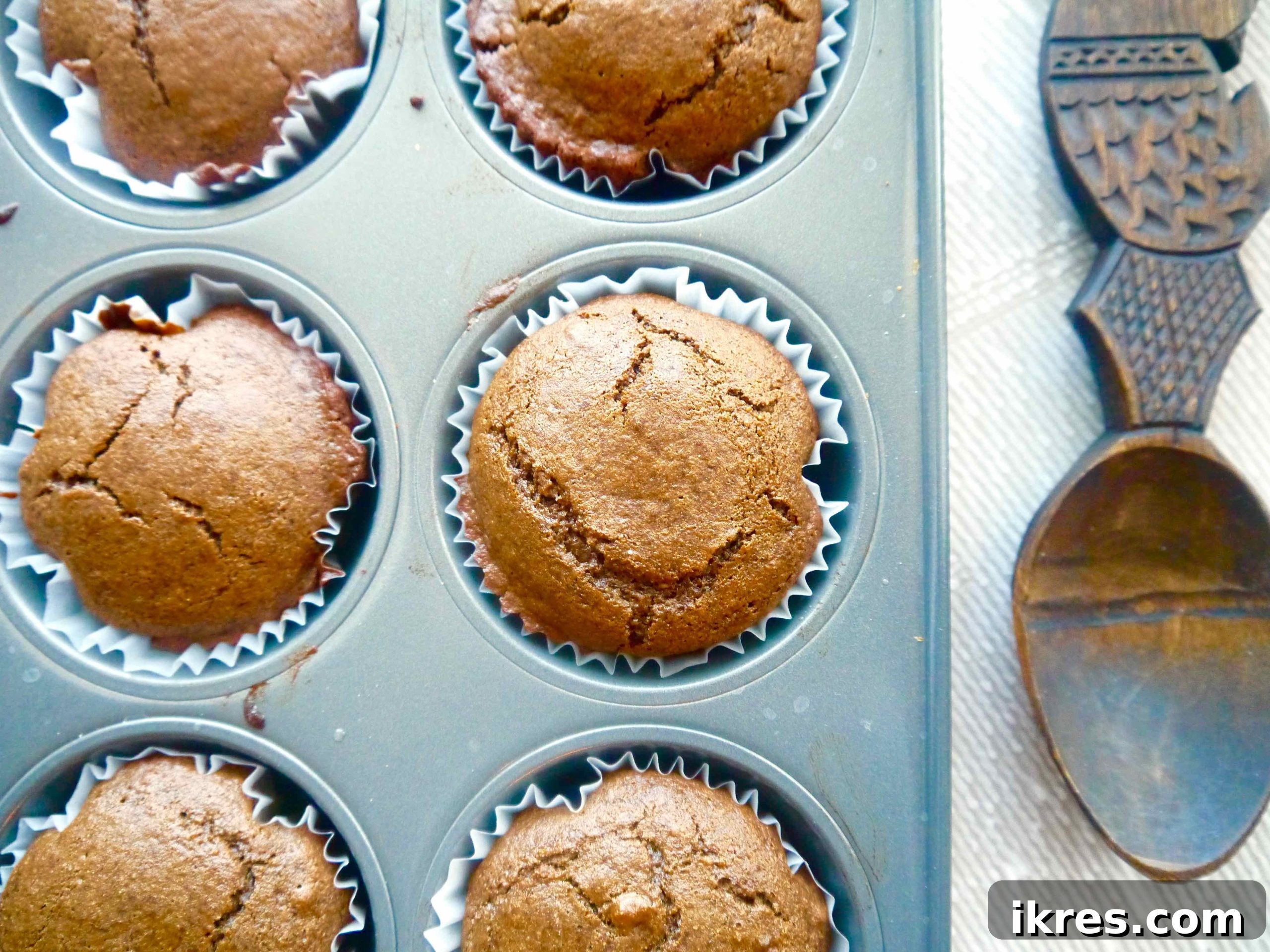 Close-up of baked chestnut flour gingerbread muffins in a muffin tin, showing their golden brown tops.