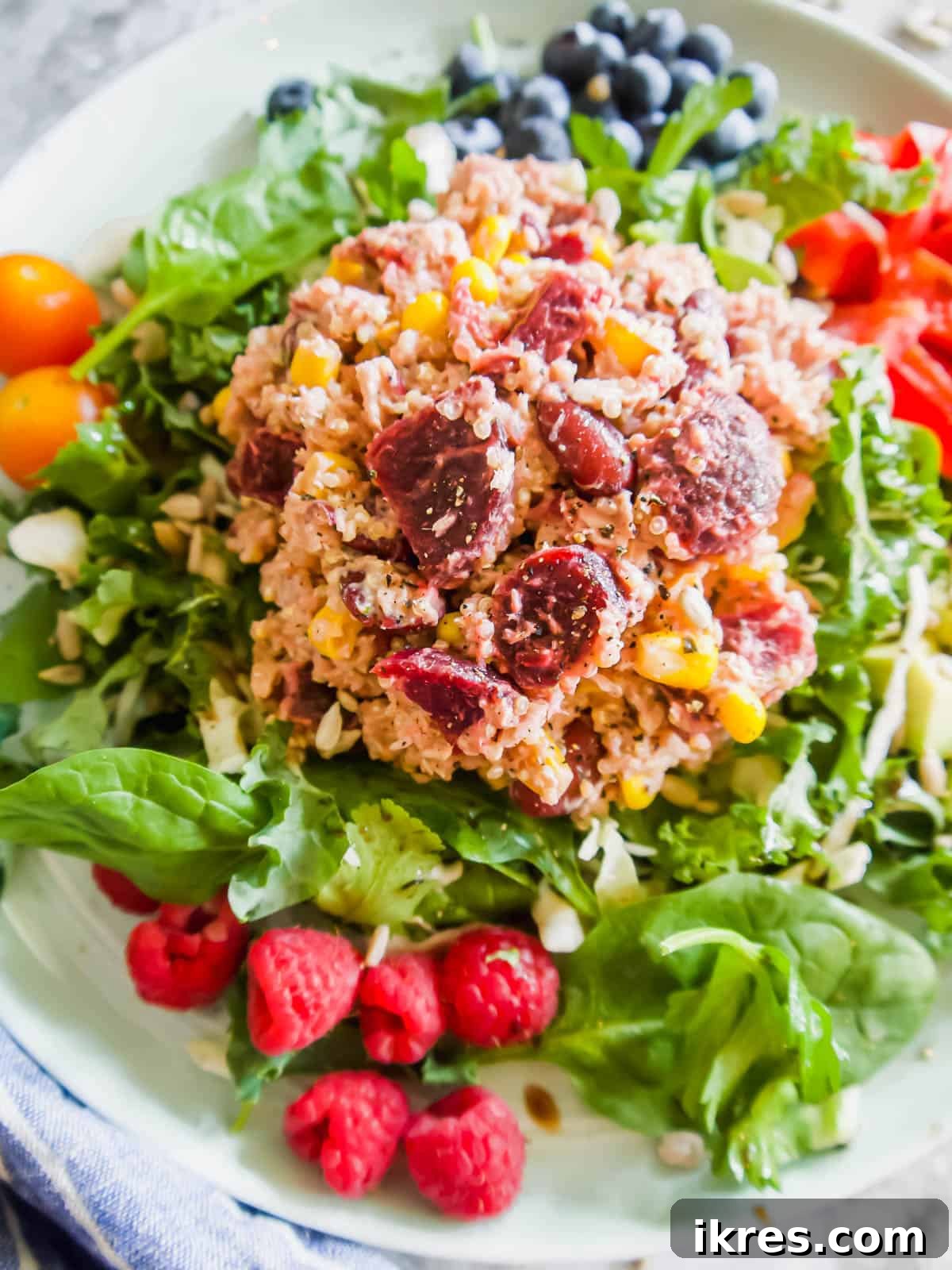 Vibrant Quinoa Beet Salad with Tuna 10 Close-up of Tuna Quinoa Salad on a plate with fresh greens and a side of fruit.