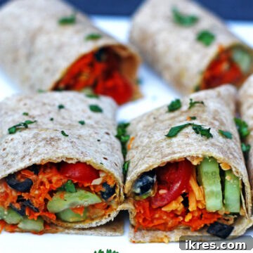 Four whole wheat veggie wraps with tomatoes, hummus, carrots, cilantro, olives, and cucumber.
