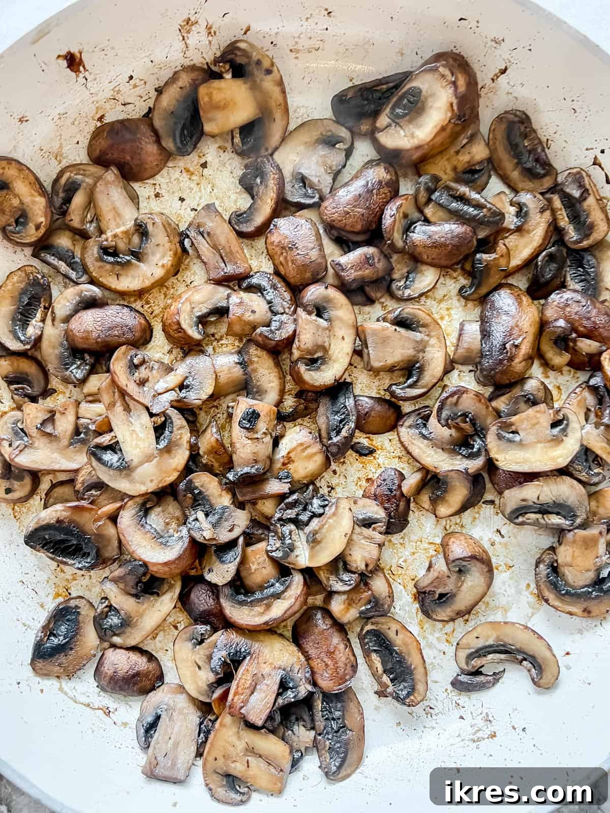 Mushrooms in a pan after being cooked until golden brown, having released their moisture and developed a rich color, forming the base of the dairy-free mushroom sauce.