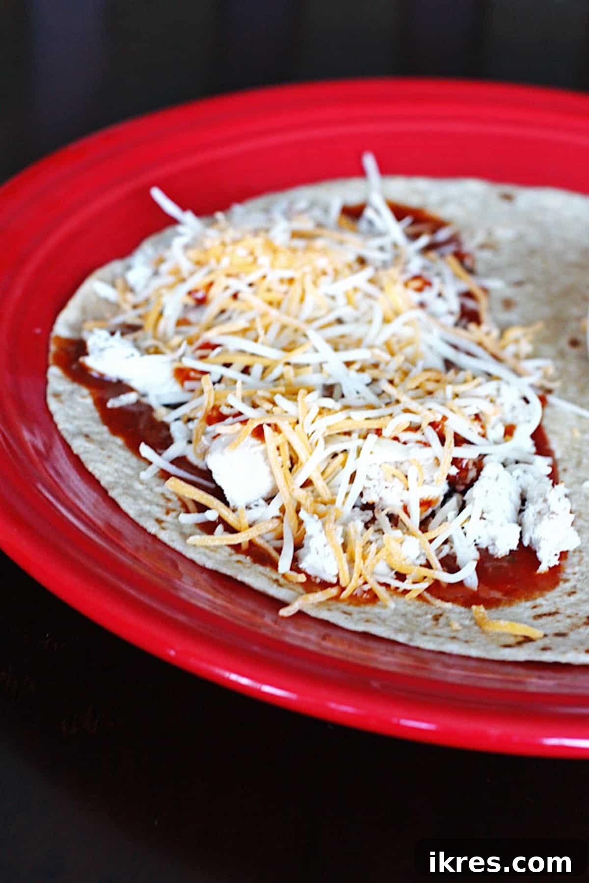 Smoky BBQ Chicken Quesadillas 3 Two halves of an assembled BBQ chicken quesadilla, ready to be folded and cooked, showing layers of chicken, barbecue sauce, and cheese on one side of a tortilla.
