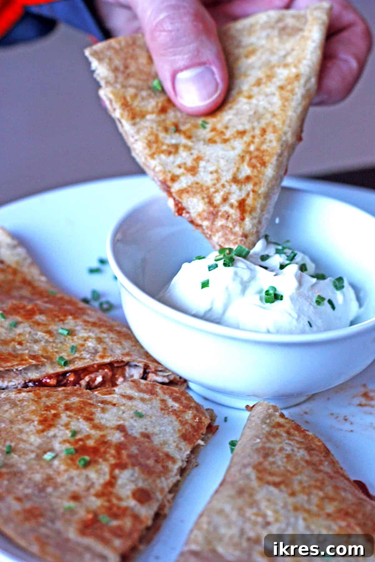 Smoky BBQ Chicken Quesadillas 4 Golden-brown BBQ Chicken Quesadillas served with a side of sour cream, ready to be enjoyed.