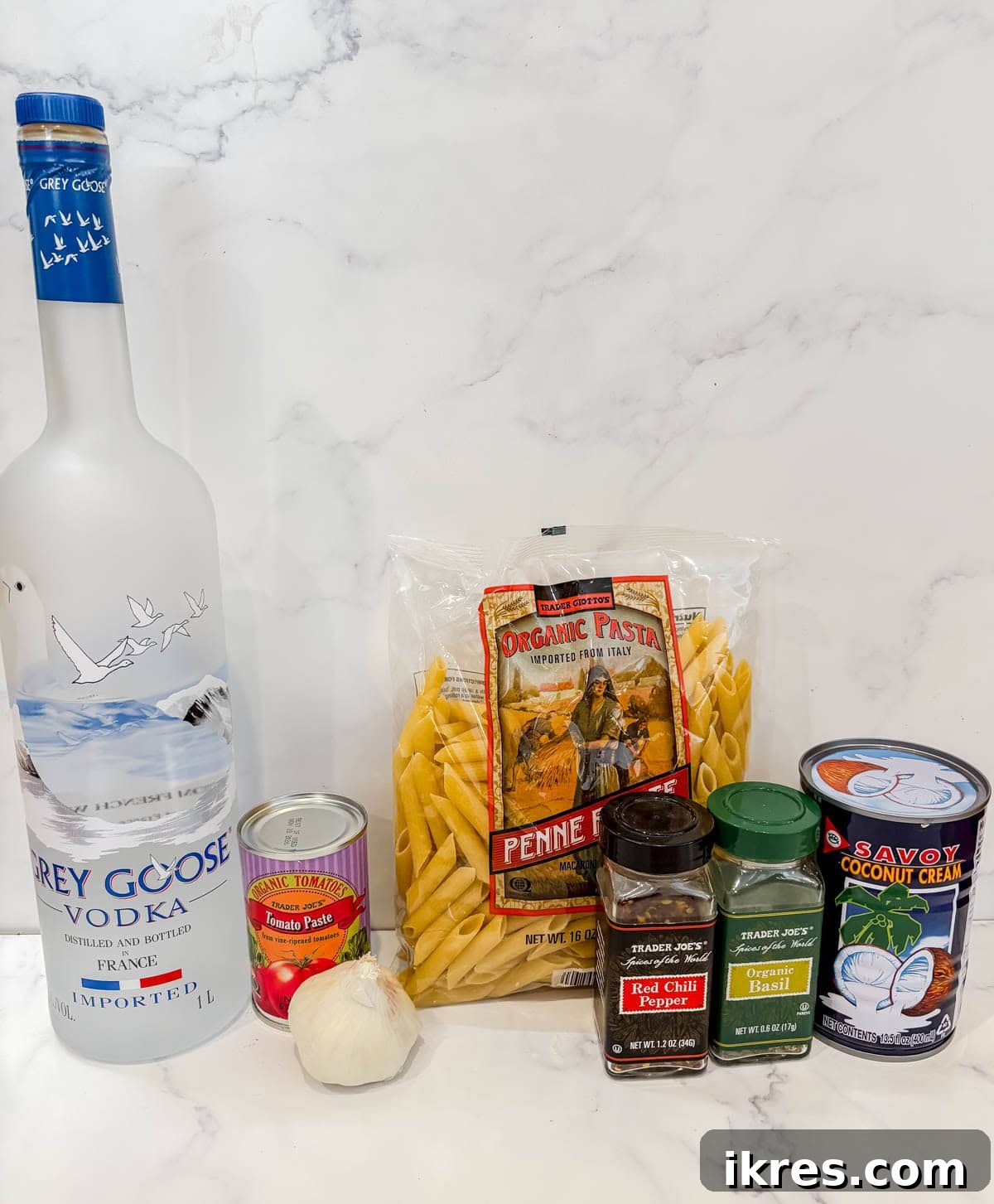 Vegan Vodka Rose Sauce 3 An array of ingredients for dairy-free vodka sauce including penne, olive oil, minced garlic, red pepper flakes, tomato paste, vodka, coconut cream, and dried basil.