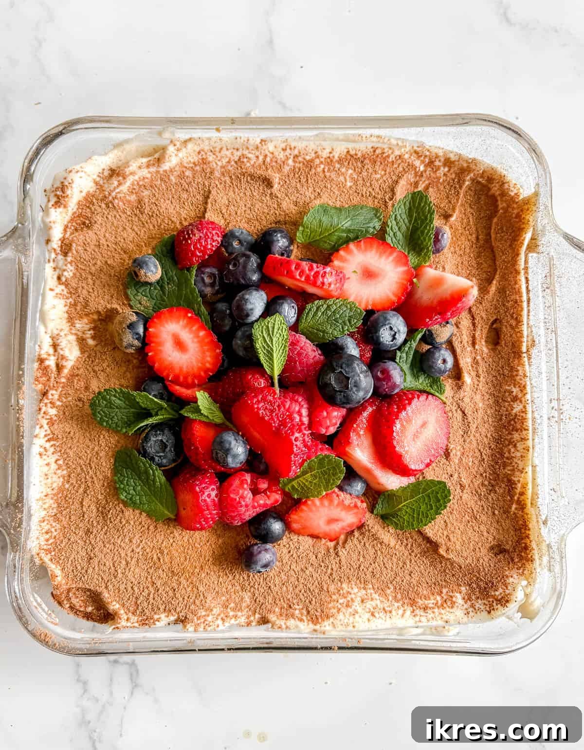 Berries and mint on top of coconut cream tiramisu.