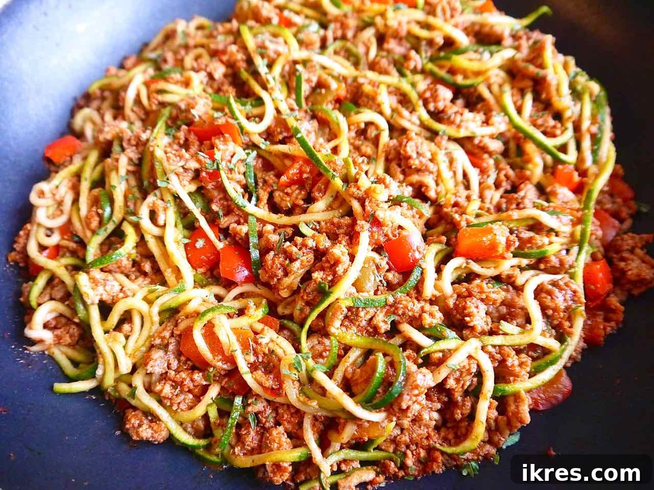 Zesty Turkey Taco Zoodle Bowls 7 The seasoned ground turkey taco meat being mixed with the cooked zucchini noodles in a pan.