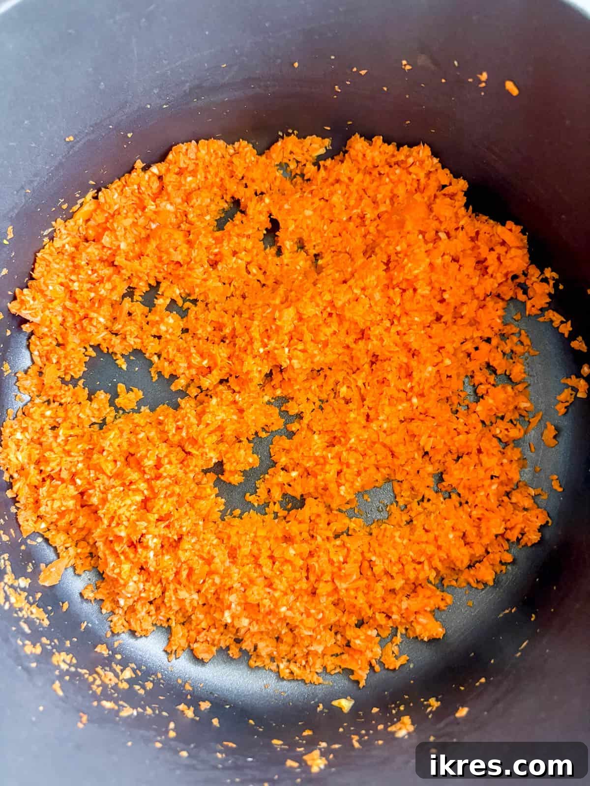 Sautéing garlic and carrots in a pan with olive oil.