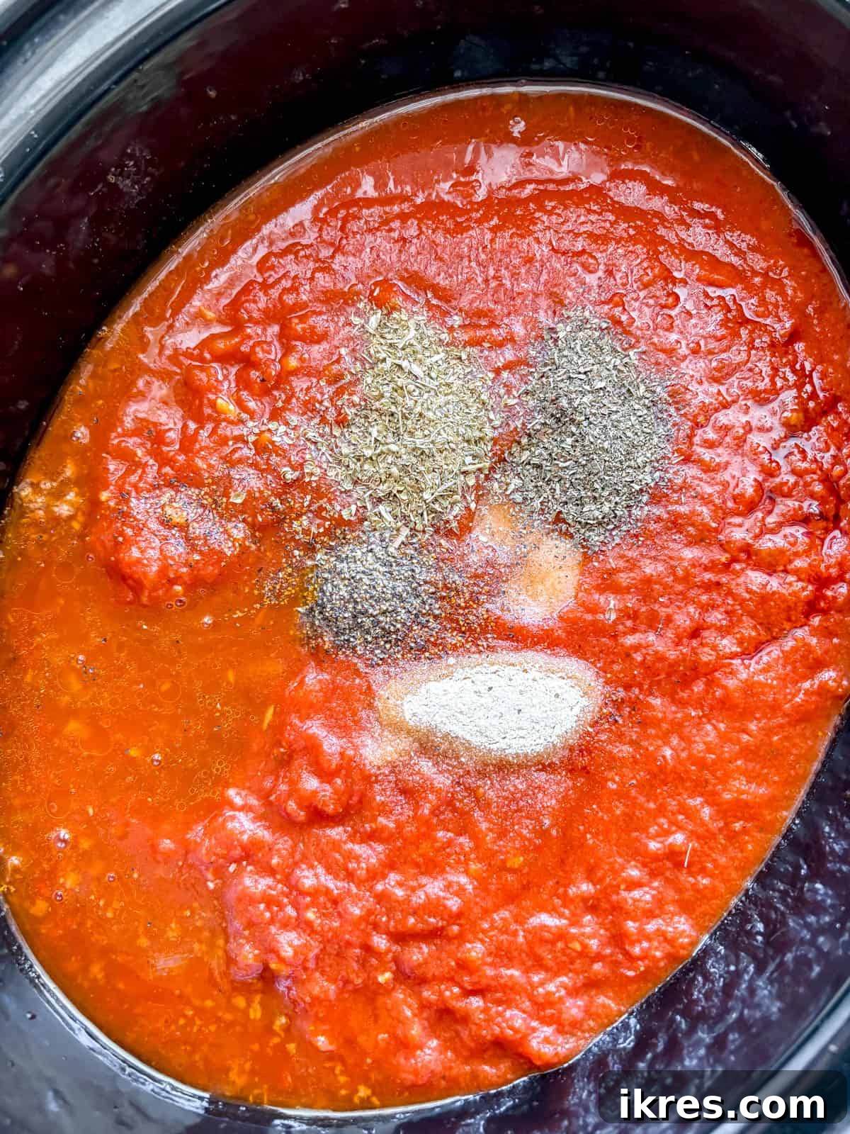 All ingredients for crockpot spaghetti sauce, including browned beef and marinara, in a slow cooker.