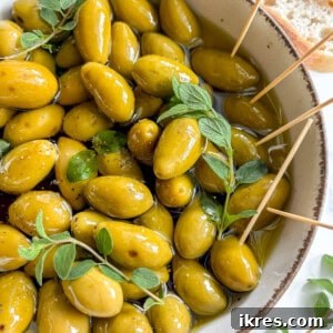 Warm Green Olives in Balsamic Vinegar and Olive oil in a bowl with toothpicks.