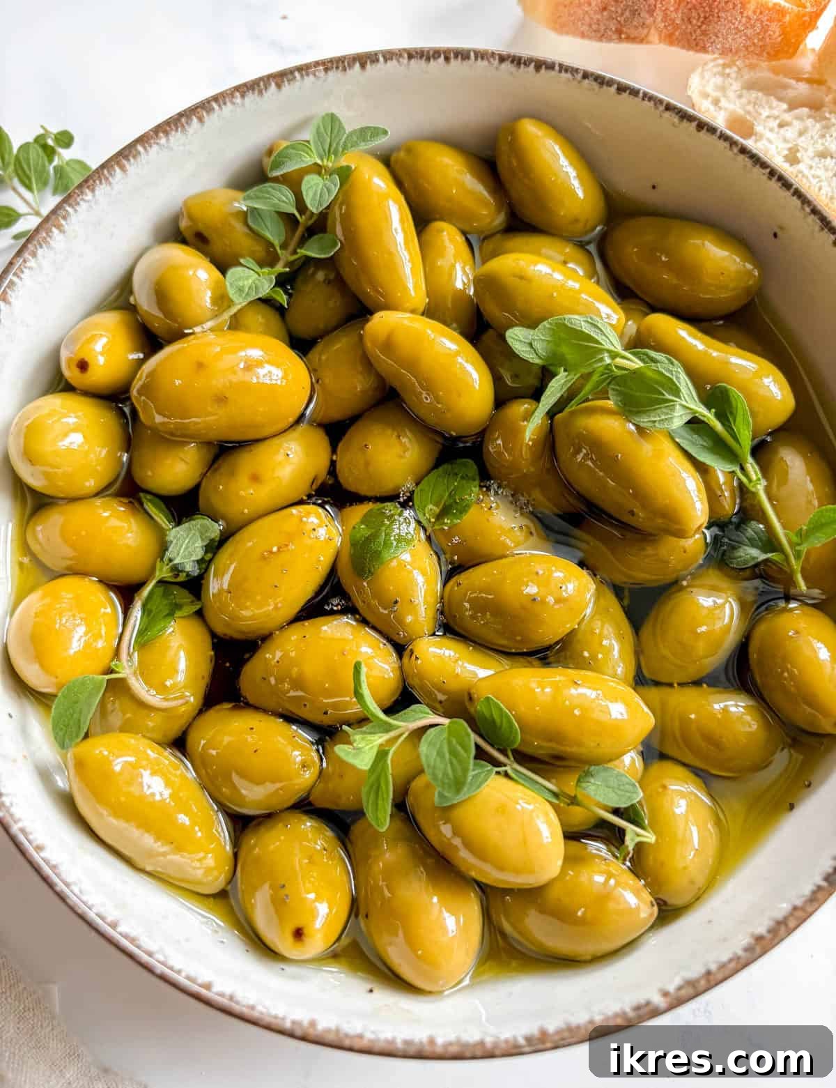 Warm Green Olives Bathed in Balsamic and Olive Oil 7 A vibrant close-up of a bowl filled with warm green olives steeped in balsamic and olive oil, expertly garnished with fresh herbs and ready for immediate enjoyment.