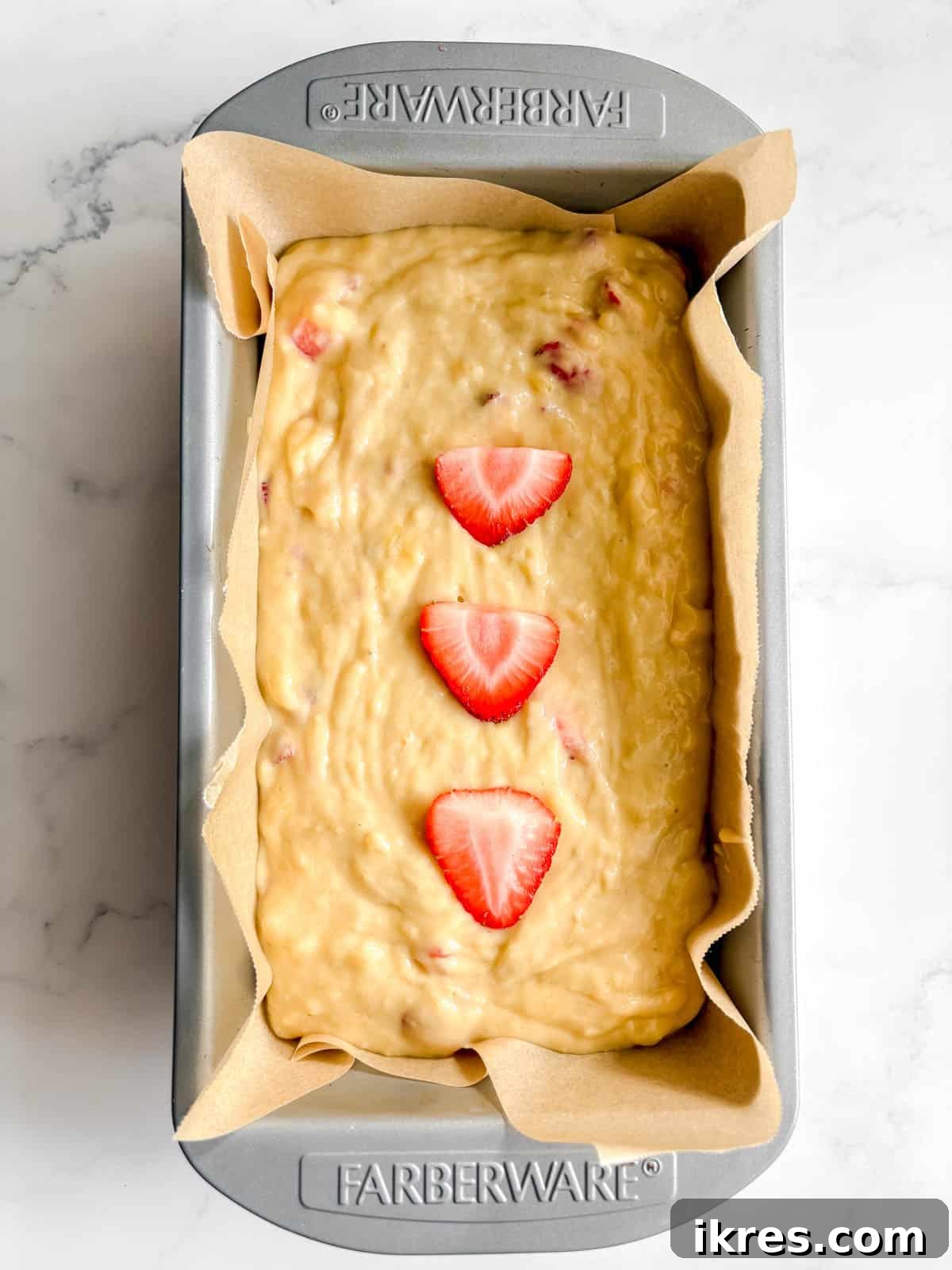 Strawberry Swirl Banana Bread 9 Strawberry banana bread batter poured into a parchment paper-lined loaf tin, ready for baking.