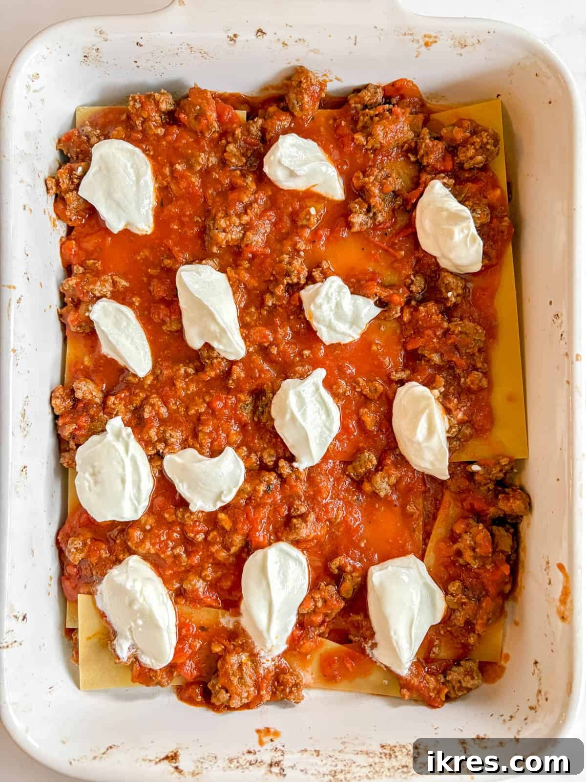 Effortless Greek Yogurt Lasagna 8 Dollops of Greek yogurt spread over a layer of meat sauce.