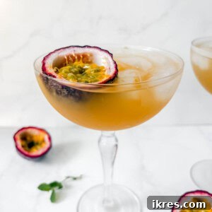 Passion fruit cocktail in a glass with half a passion fruit in the glass.