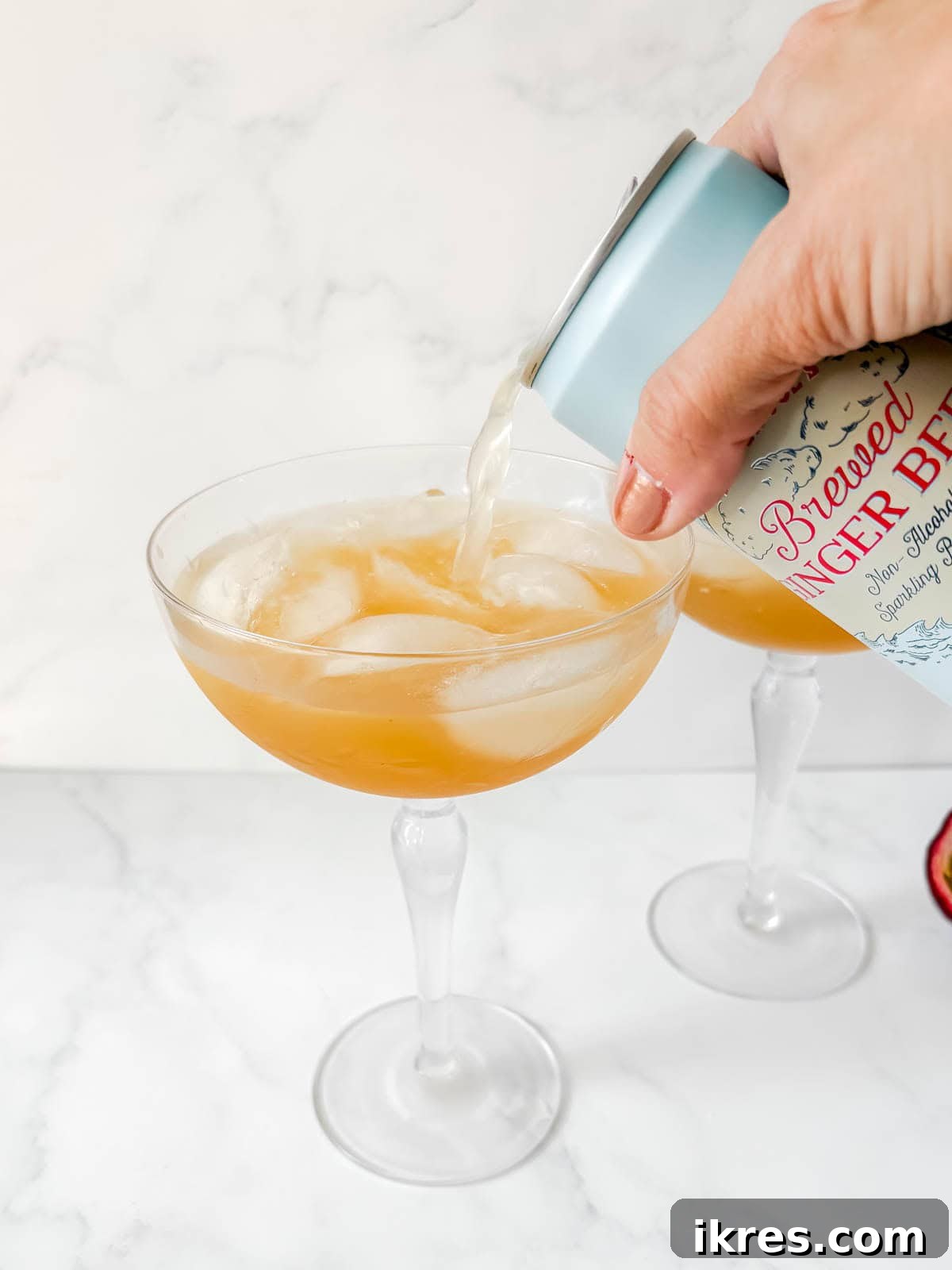 Pouring ginger beer on top of the drink.