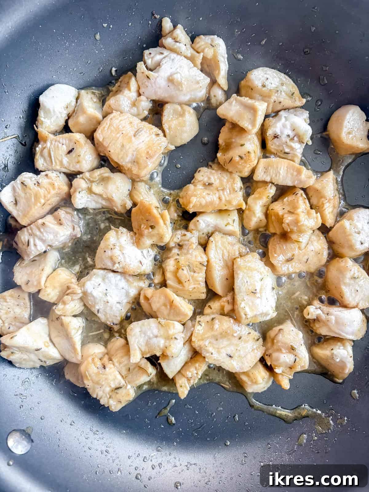 Chicken, lemon, maple syrup and herbs in a pan cooking.