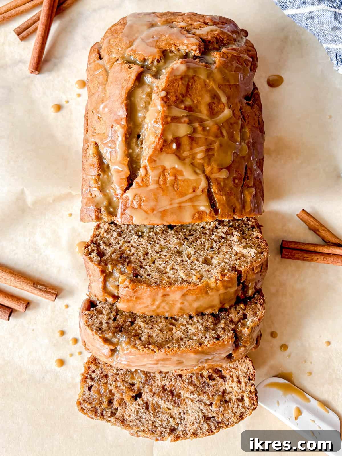 Maple banana bread with maple glaze sliced on a board.