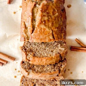 Maple banana bread with maple glaze sliced on a board.