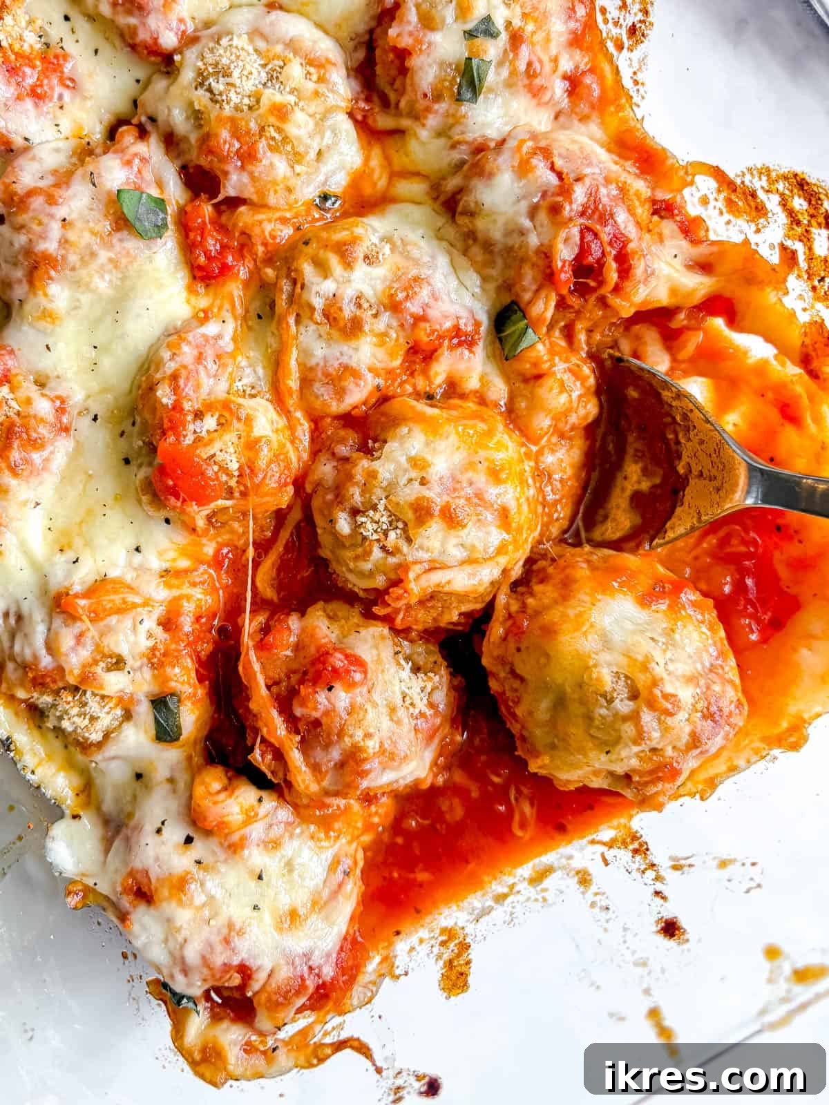Chicken Parmesan Meatballs in a dish with a spoon reaching to spoon one out.