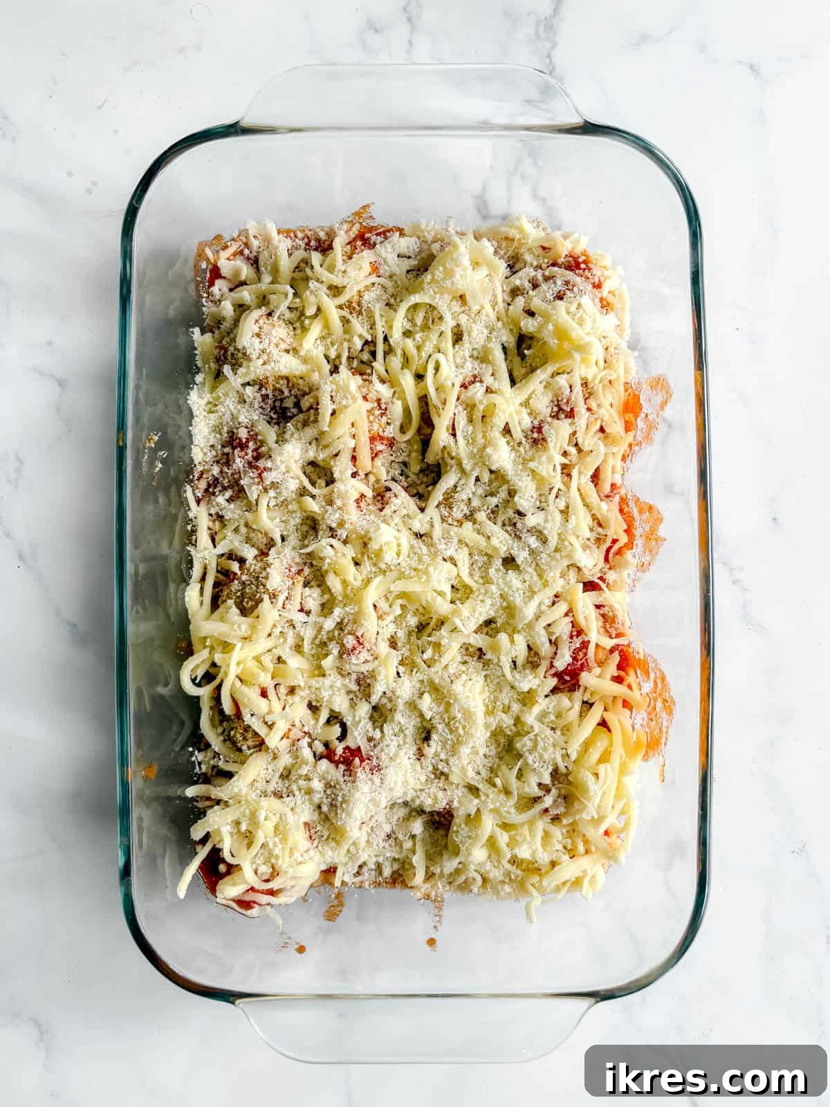 Chicken parm meatballs covered in cheese before baking the cheese.