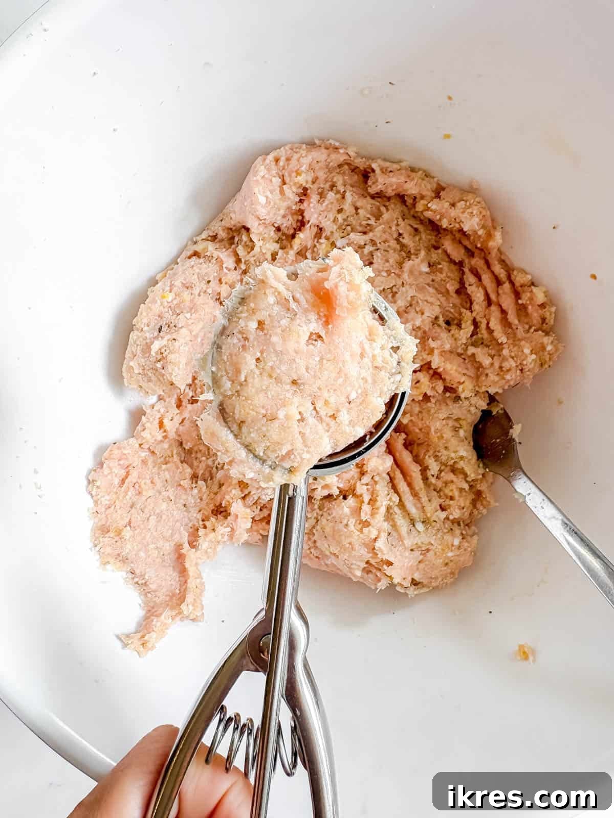Rolling a meatball with a cookie scoop.