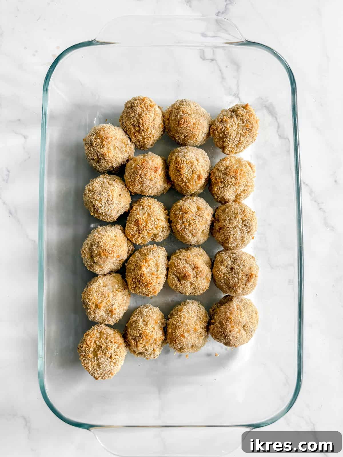 Chicken parmesan meatballs in a baking dish.